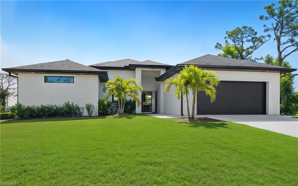 Contemporary stucco exterior with a dark shingle roof, integrated two-car garage, and a lush green lawn