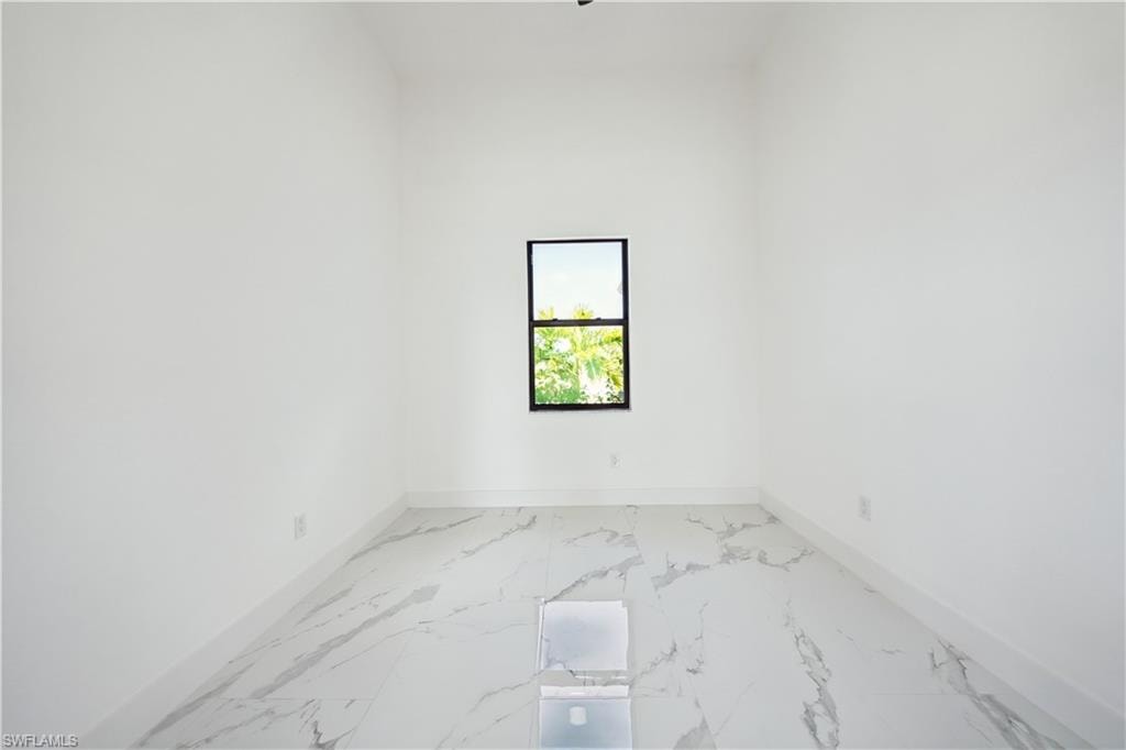 Bright interior space featuring a single window with a black frame, white walls, and white baseboards