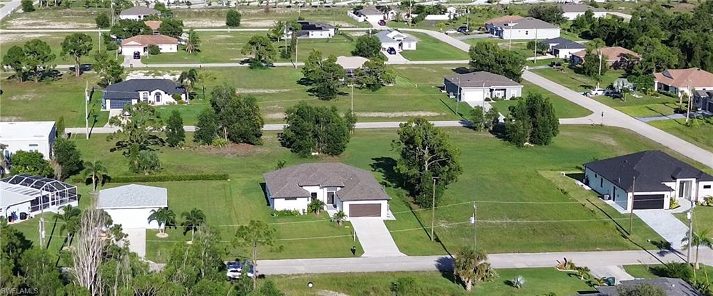 Aerial perspective highlighting a single-story residence with a light-colored exterior and an attached garage