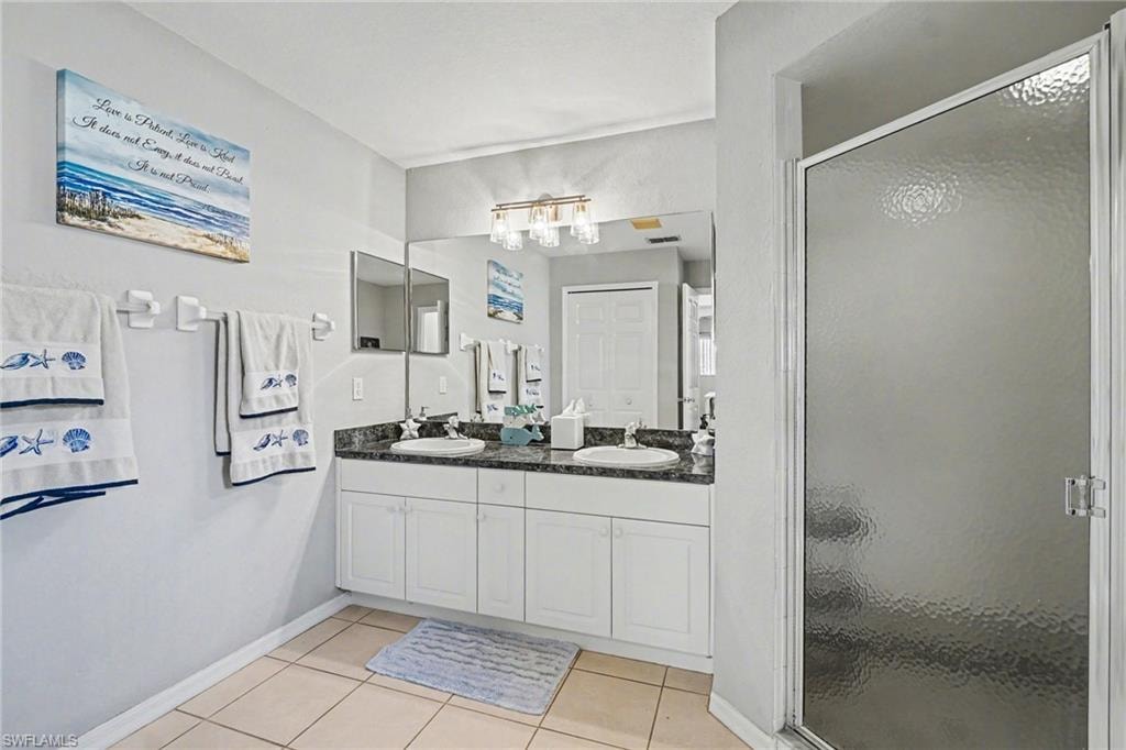 Bathroom featuring a double vanity with white cabinetry, a dark countertop, and dual undermount sinks