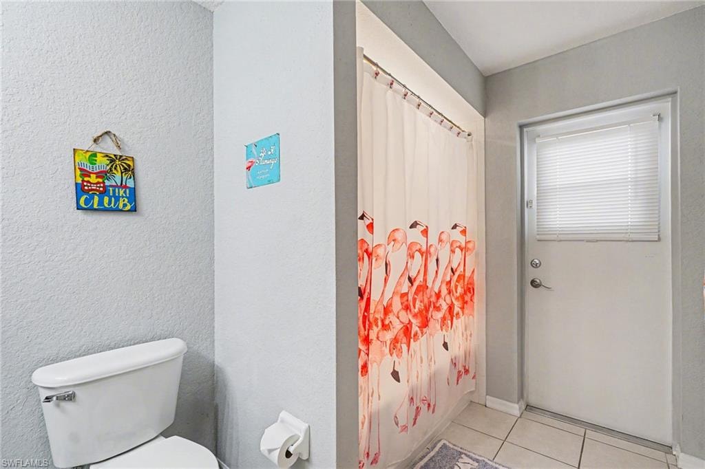 White toilet with a built-in toilet paper holder and light gray wall finishes