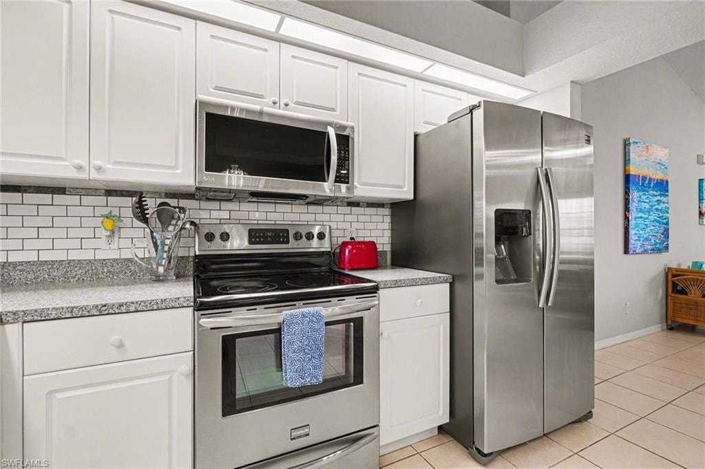 Modern kitchen featuring stainless steel appliances, white cabinetry, a subway tile backsplash, and a side-by-side refrigerator with an ice and water dispenser