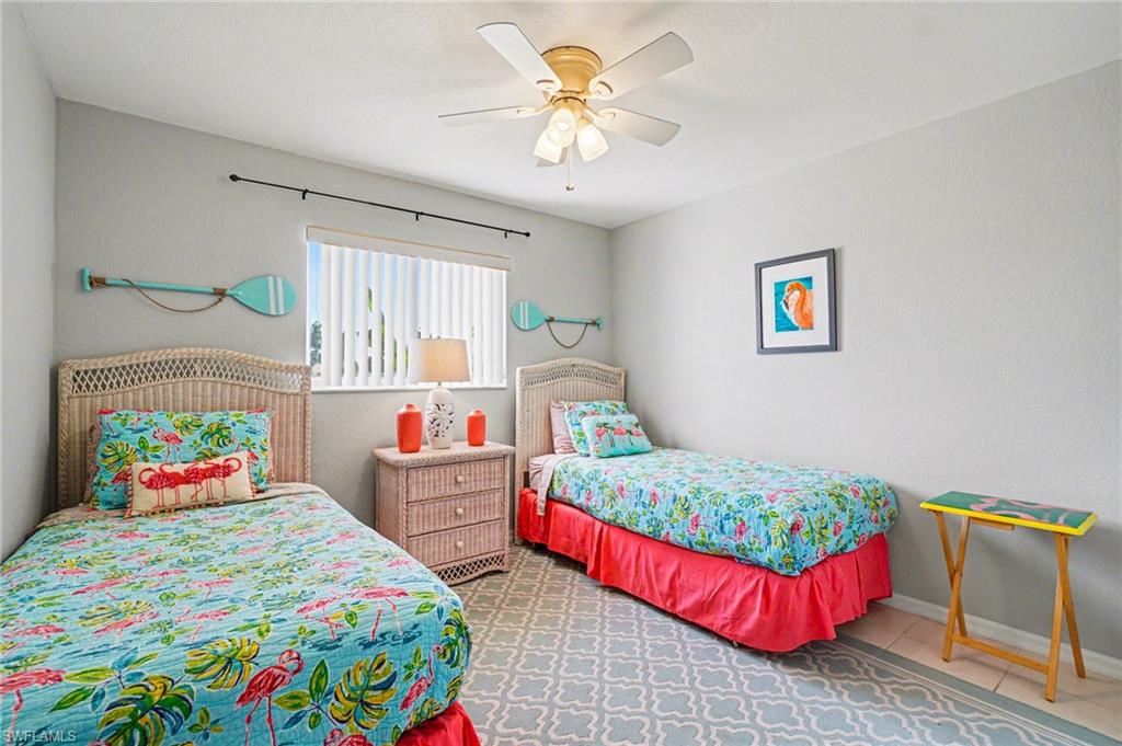 Room featuring two single beds with woven headboards, a window with blinds, and a ceiling fan