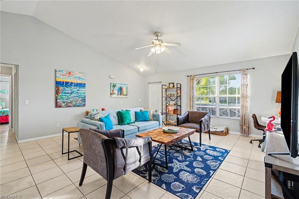 Spacious living area featuring vaulted ceilings, large windows with blinds, and light-toned tile flooring