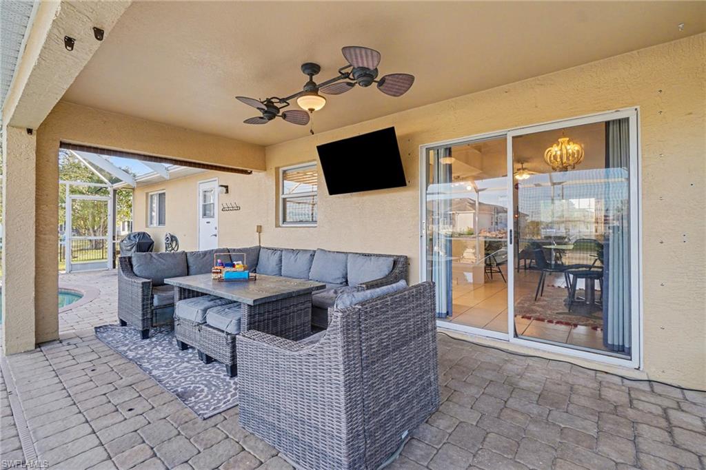 Covered patio featuring paver flooring, multiple ceiling fans with lighting, and direct access to an enclosed pool area