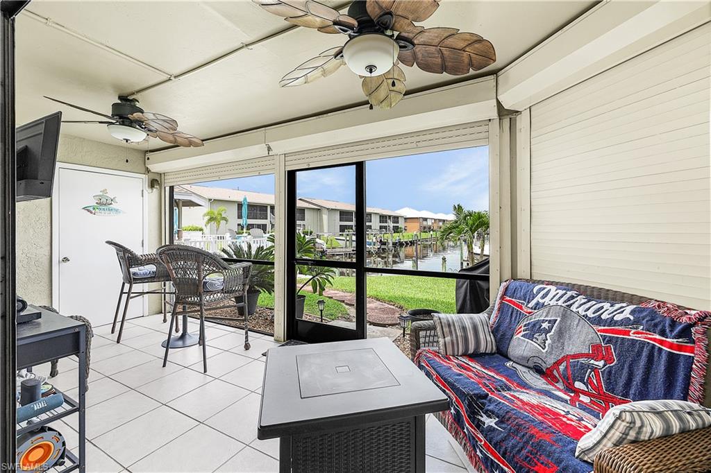Screened porch featuring white tile flooring, two ceiling fans, and clear water frontage