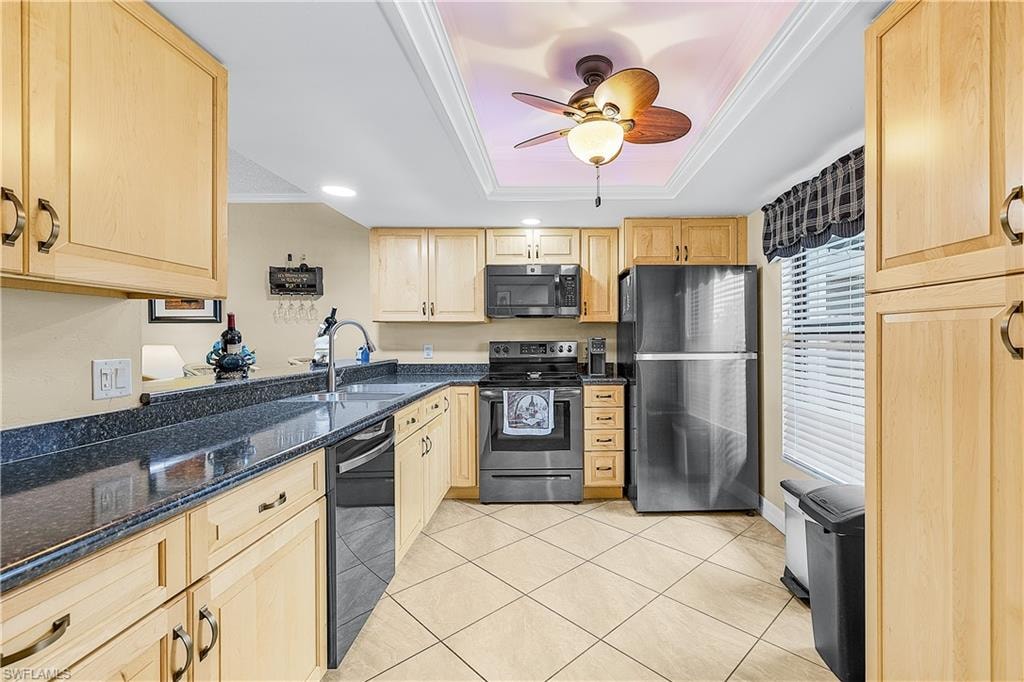 Kitchen featuring light wood cabinetry, dark countertops, and stainless steel appliances