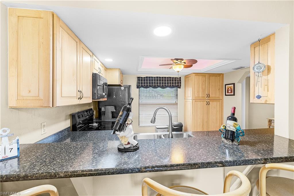 Kitchen featuring light wood cabinetry, dark speckled countertops, and a built-in double oven