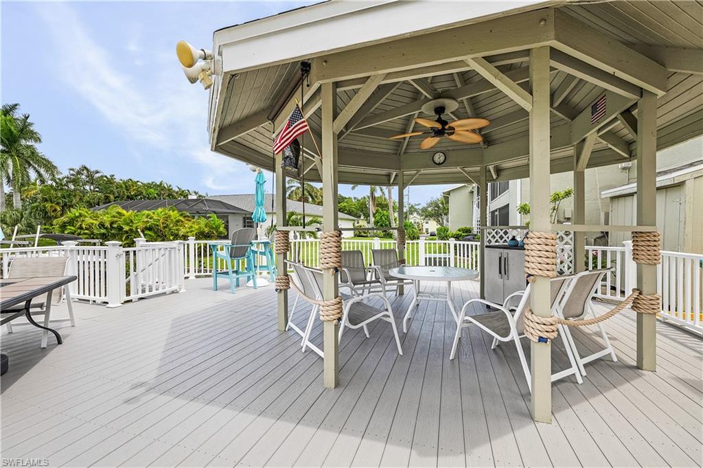 Expansive outdoor deck featuring a hexagonal gazebo with a built-in ceiling fan, white railing, rope accents, and a built-in outdoor cooking station