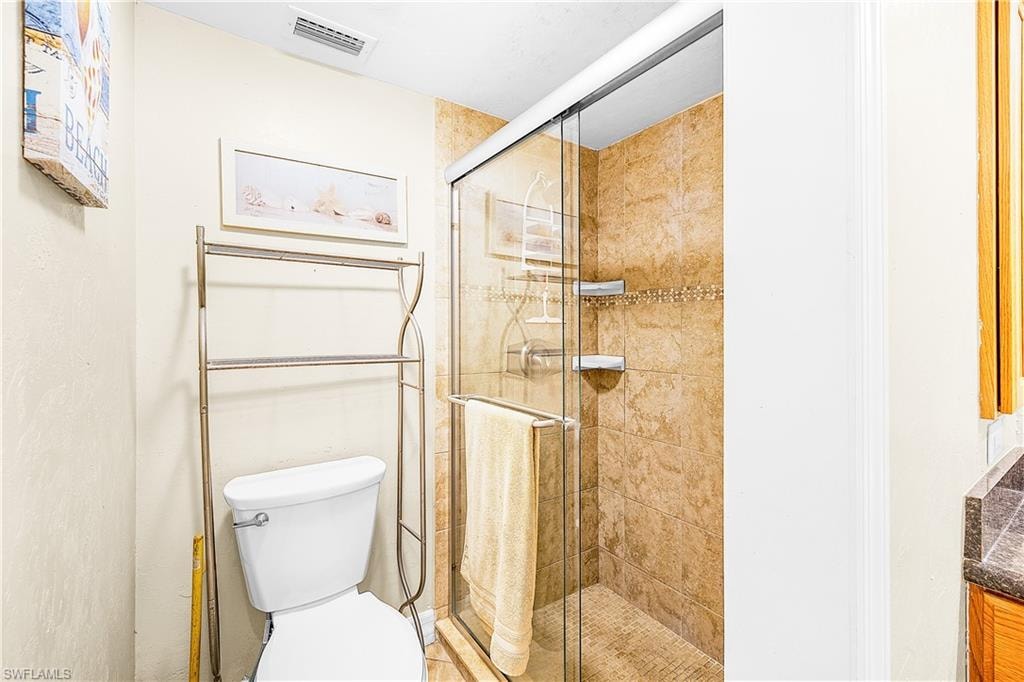 Tiled shower enclosure with sliding glass door, mosaic accent tile, and built-in shelving