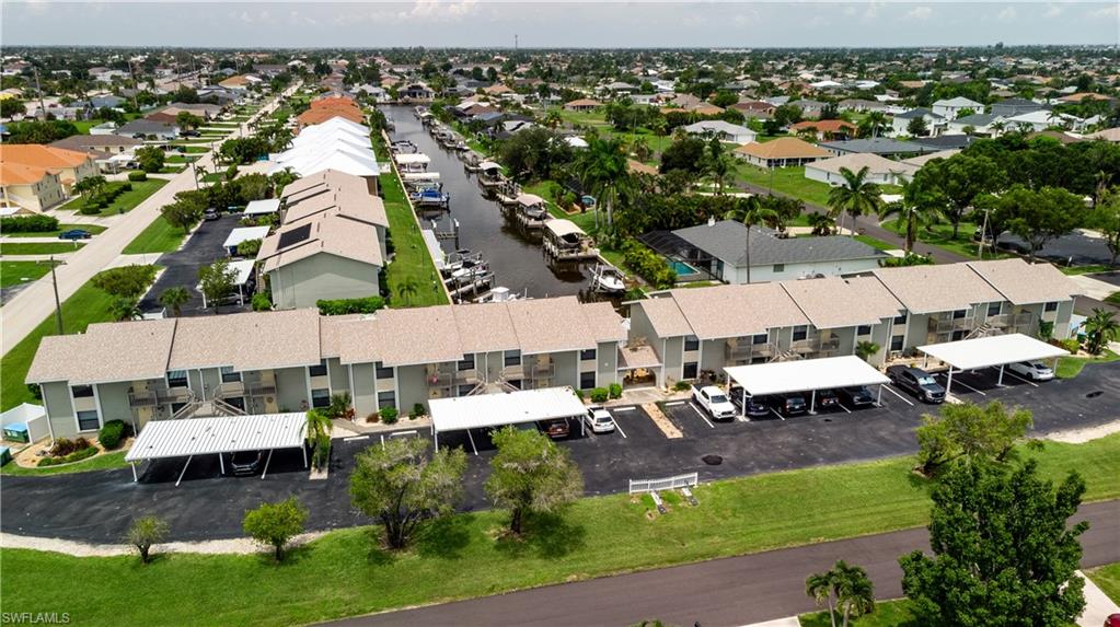 Waterfront condominium community featuring a canal with multiple boat docks, carports, and mature landscaping