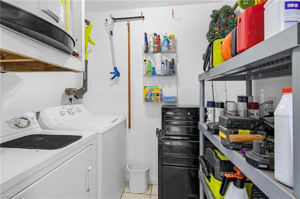 Dedicated laundry area featuring a white washing machine and dryer, a built-in overhead shelf, and tile flooring