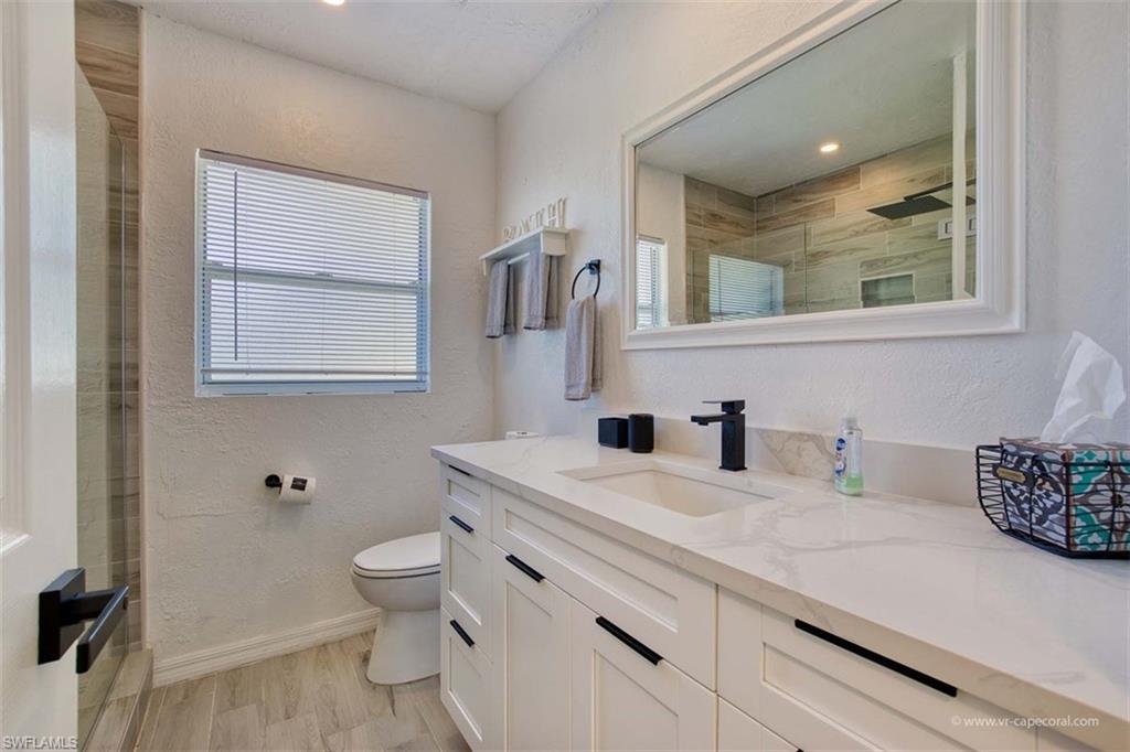 Bathroom featuring a large vanity with white cabinetry, a light-toned countertop, and a rectangular undermount sink with a matte black faucet