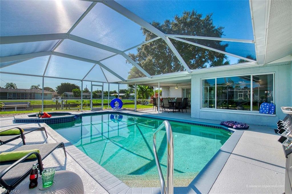 Screened lanai featuring a swimming pool, integrated spa, and expansive patio area with direct access to an outdoor dining space