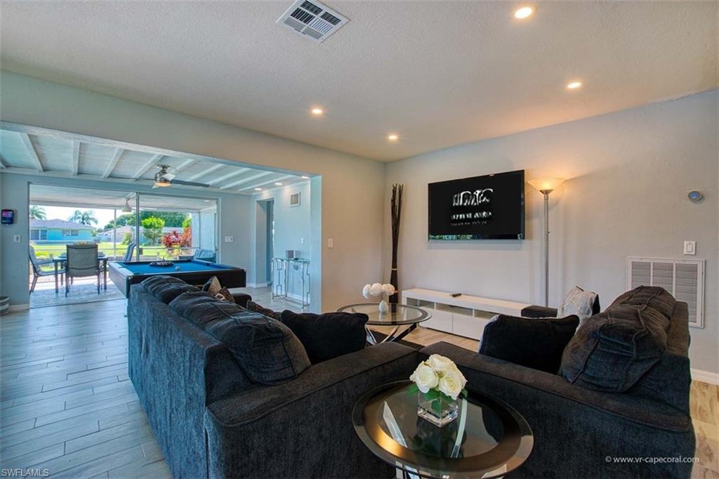 Open concept living space featuring wood-finish flooring, recessed lighting, and a wall-mounted television