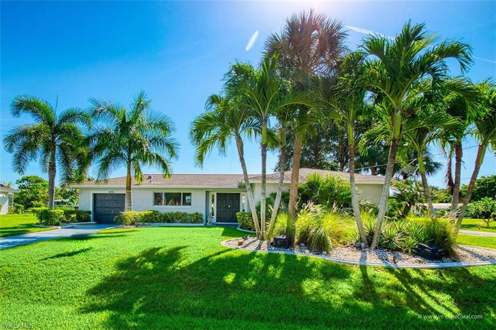 Manicured front lawn with mature palm trees and lush landscaping