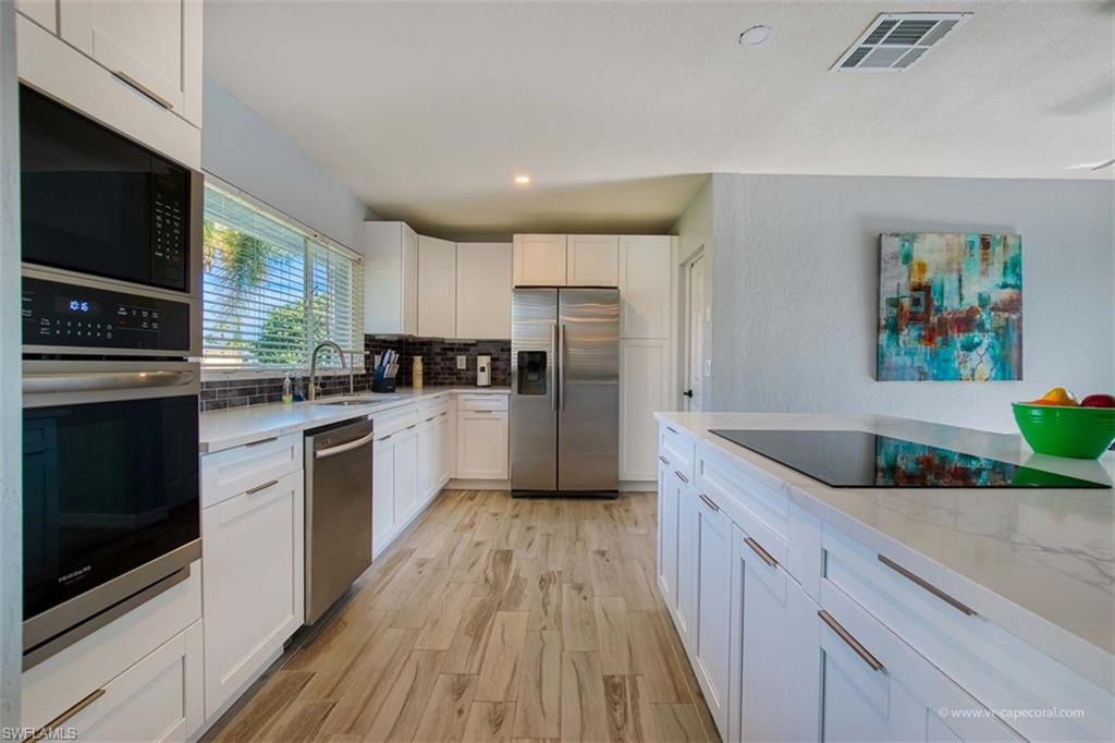 Contemporary kitchen featuring white cabinetry, light-toned countertops, and wood-finish flooring