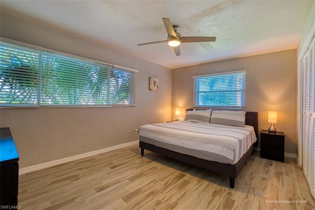 Interior room featuring wood-finish tile flooring, a ceiling fan with integrated lighting, and multiple windows with horizontal blinds