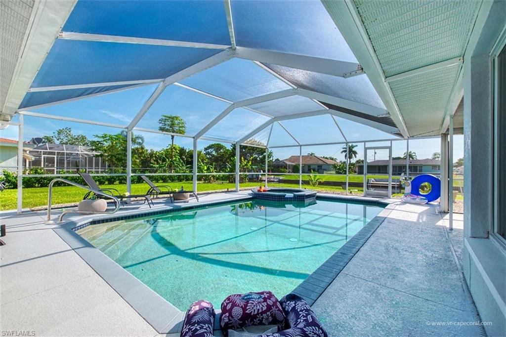 Screened outdoor living area featuring a rectangular pool with an integrated spa