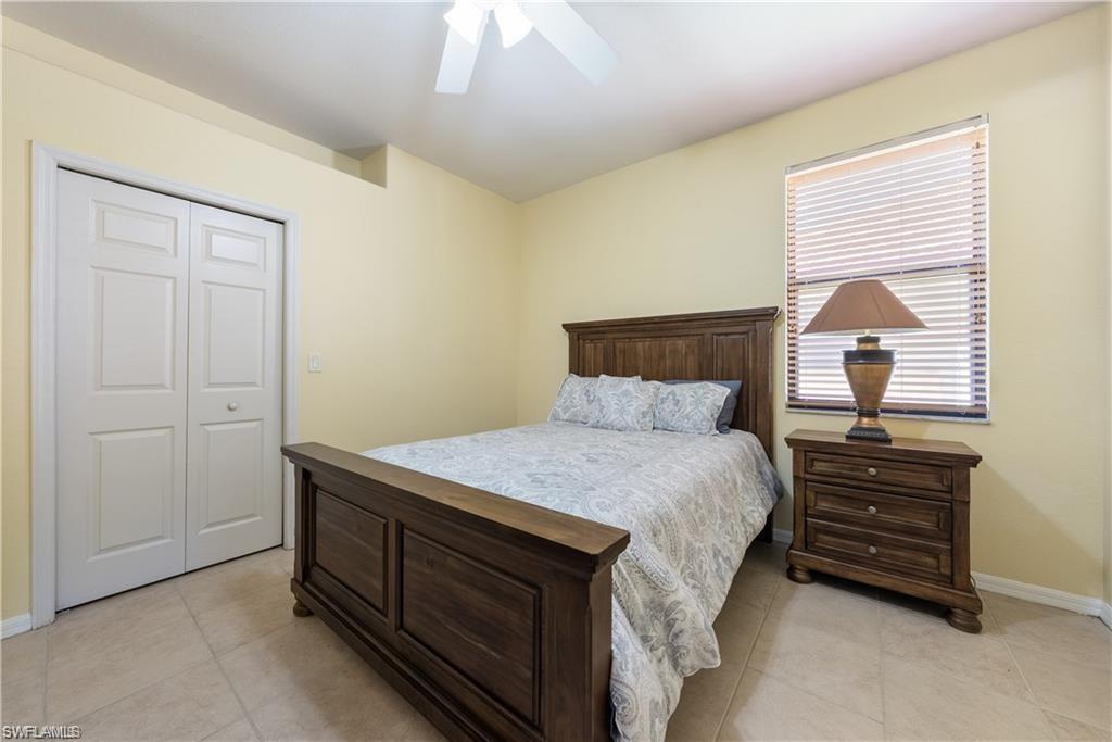 Bedroom featuring a closet, light tile patterned floors, and ceiling fan