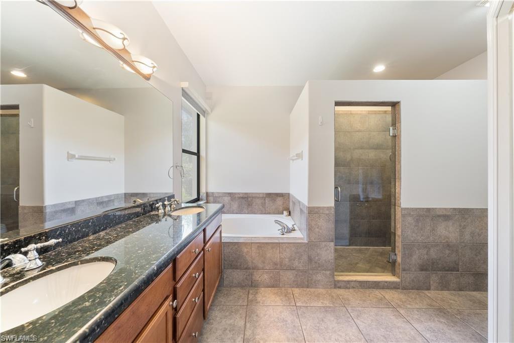 Full bathroom featuring double vanity, a garden tub, a stall shower, light tile patterned floors, and recessed lighting