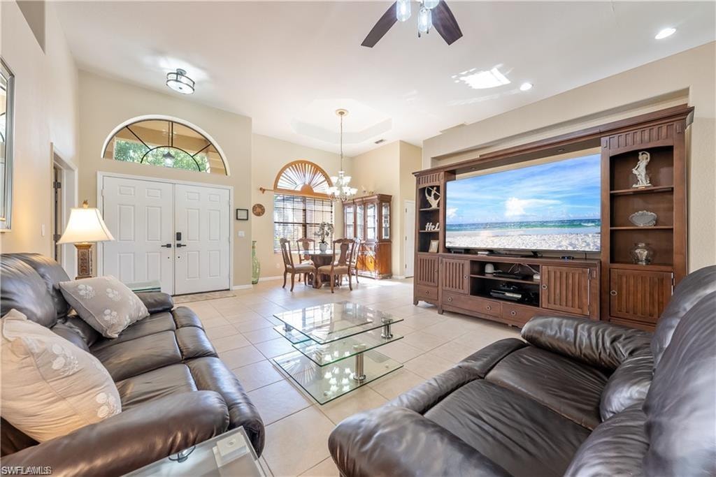 Living area featuring light tile patterned flooring, a chandelier, and a ceiling fan