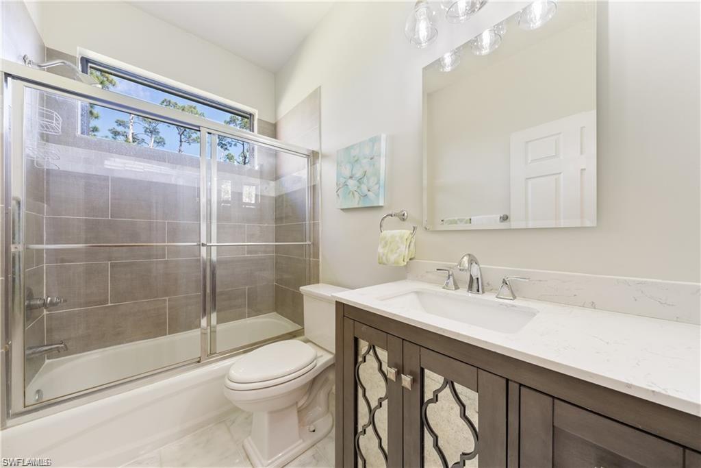 Bathroom with vanity and combined bath / shower with glass door