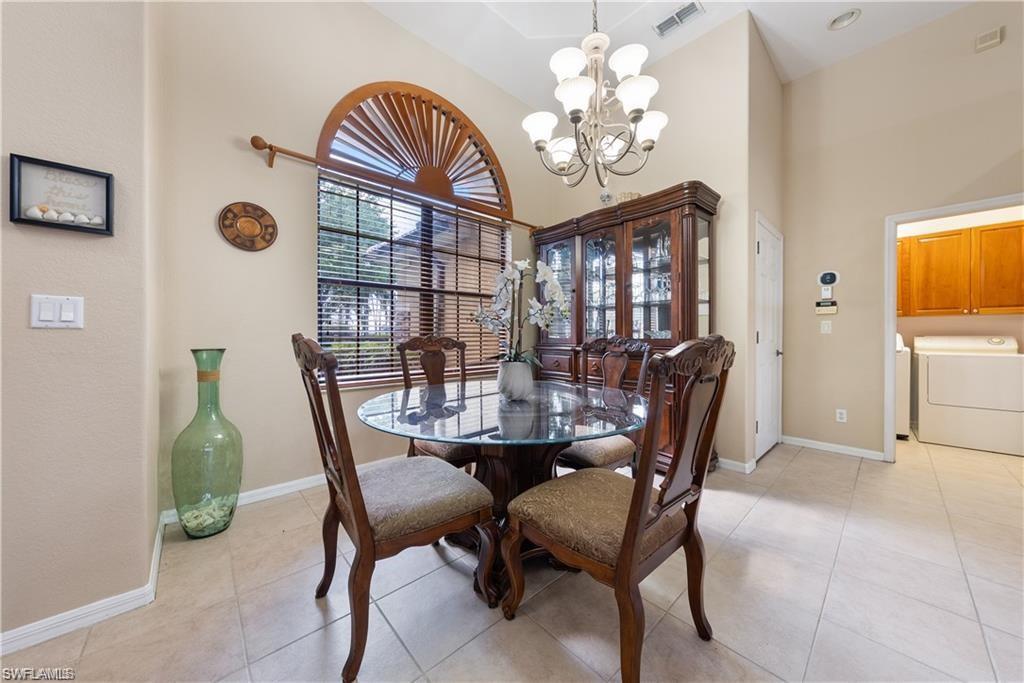Dining space with a towering ceiling, light tile patterned floors, a chandelier, and washing machine and clothes dryer