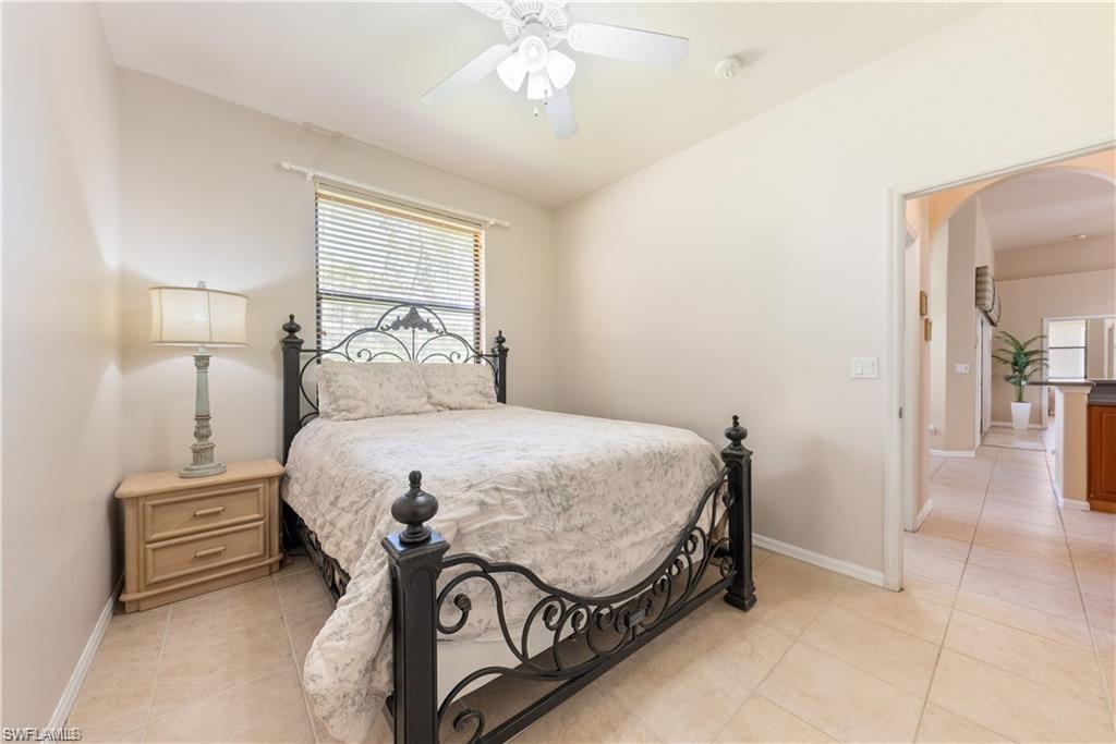 Bedroom featuring arched walkways, light tile patterned flooring, and a ceiling fan