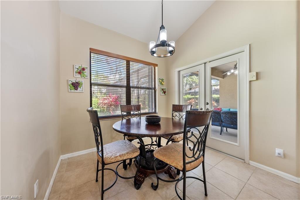 Dining area featuring light tile patterned floors, vaulted ceiling, a chandelier, and french doors