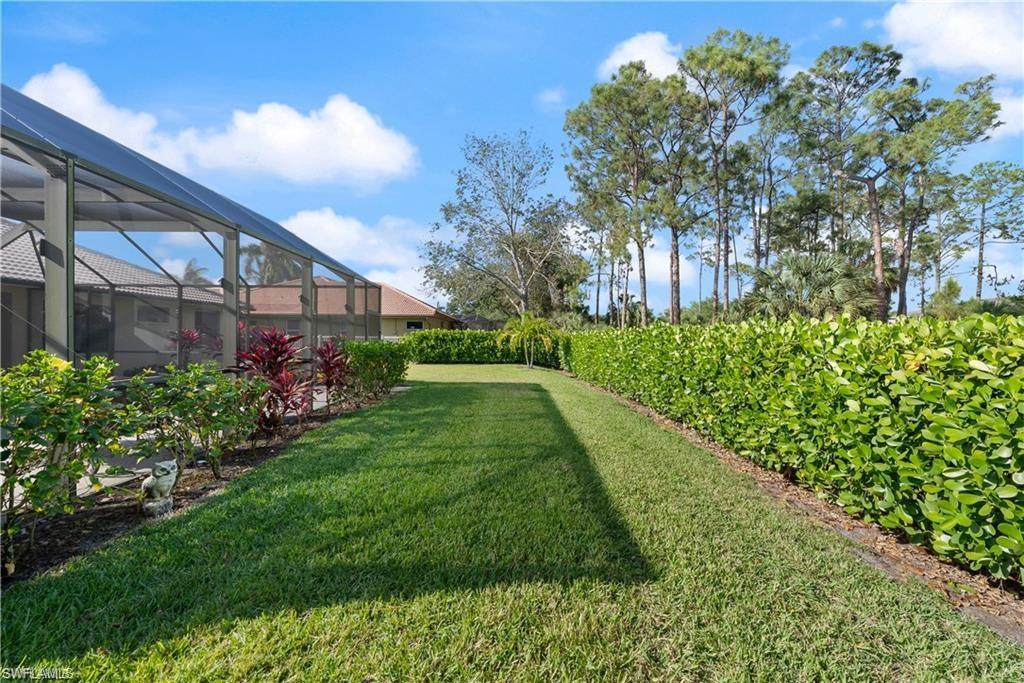 View of grassy yard with a lanai and a sunroom