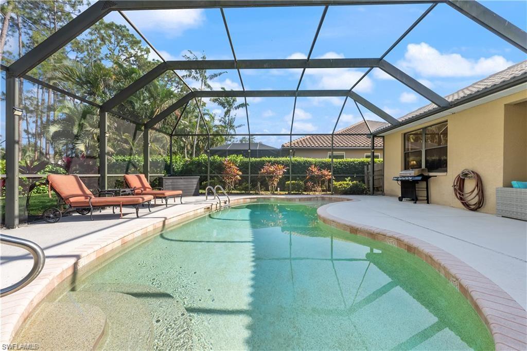 Outdoor pool featuring glass enclosure, a sunroom, a patio, and grilling area