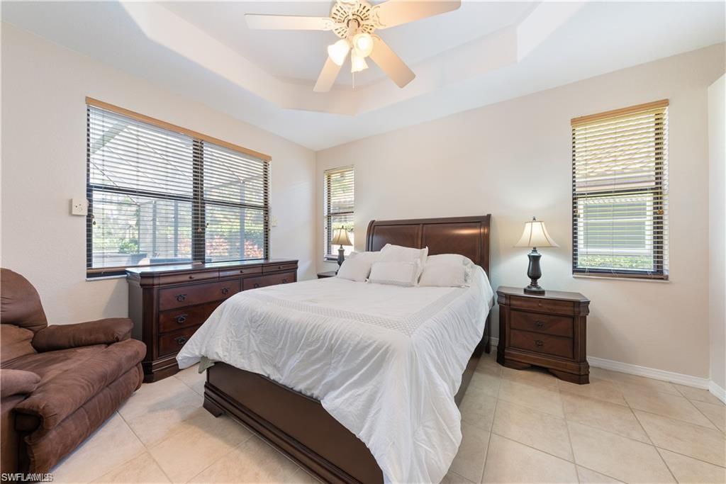 Bedroom with a raised ceiling, a ceiling fan, and light tile patterned floors