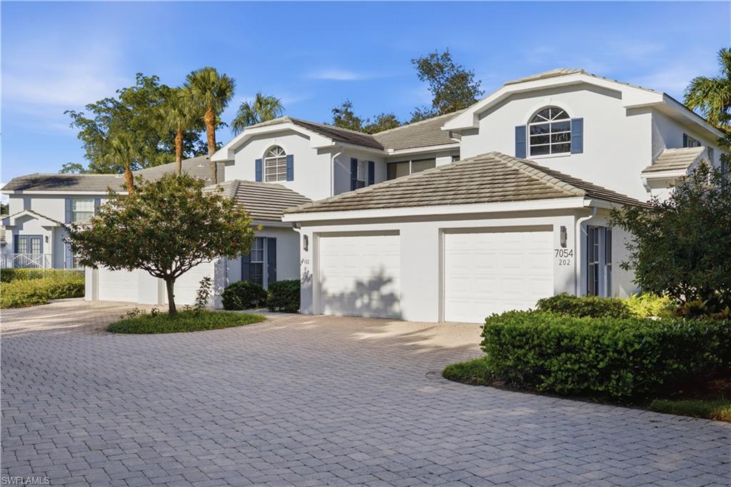 Mediterranean-style exterior featuring a tile roof, stucco finish, arched window accents, and blue shutters