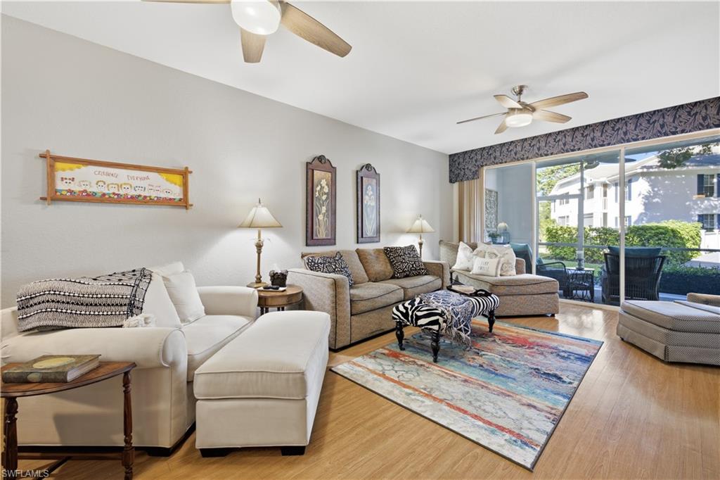Living area featuring wood-finish flooring, light neutral wall paint, and ceiling fans with integrated lighting