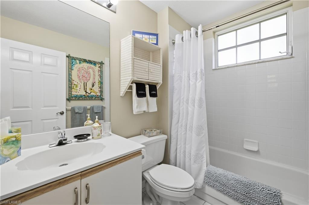 White vanity with wood-finish trim, undermount sink, and wall-mounted mirror