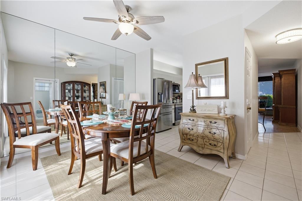Dining area featuring a full-wall mirror, ceiling fan with integrated lighting, and tile flooring