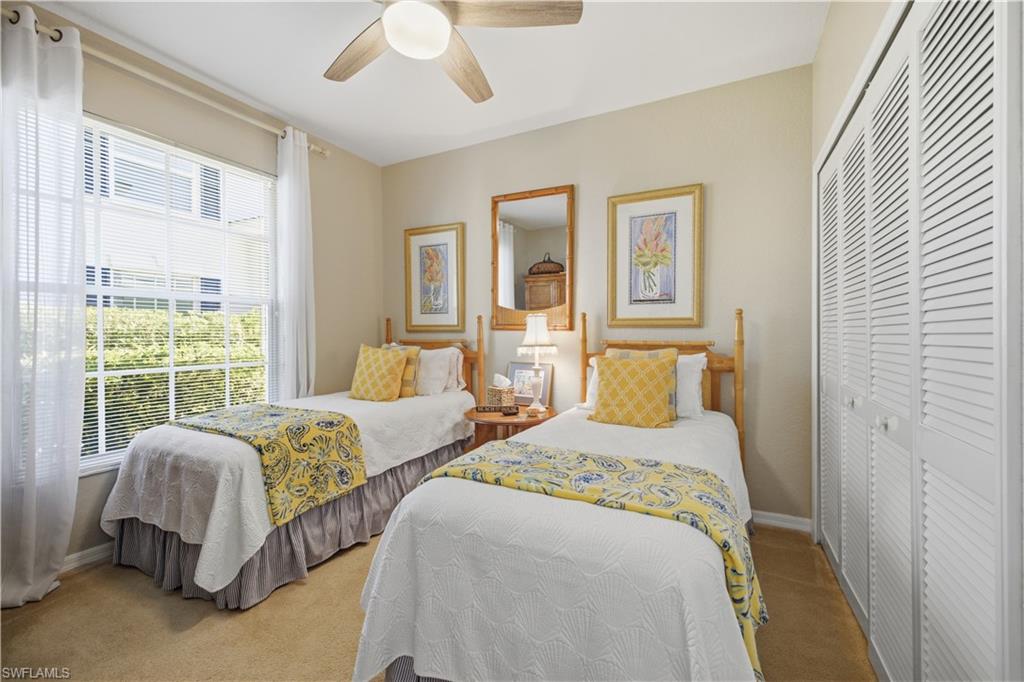 Bedroom featuring a large window, louvered bi-fold closet doors, a ceiling fan, and neutral wall tones