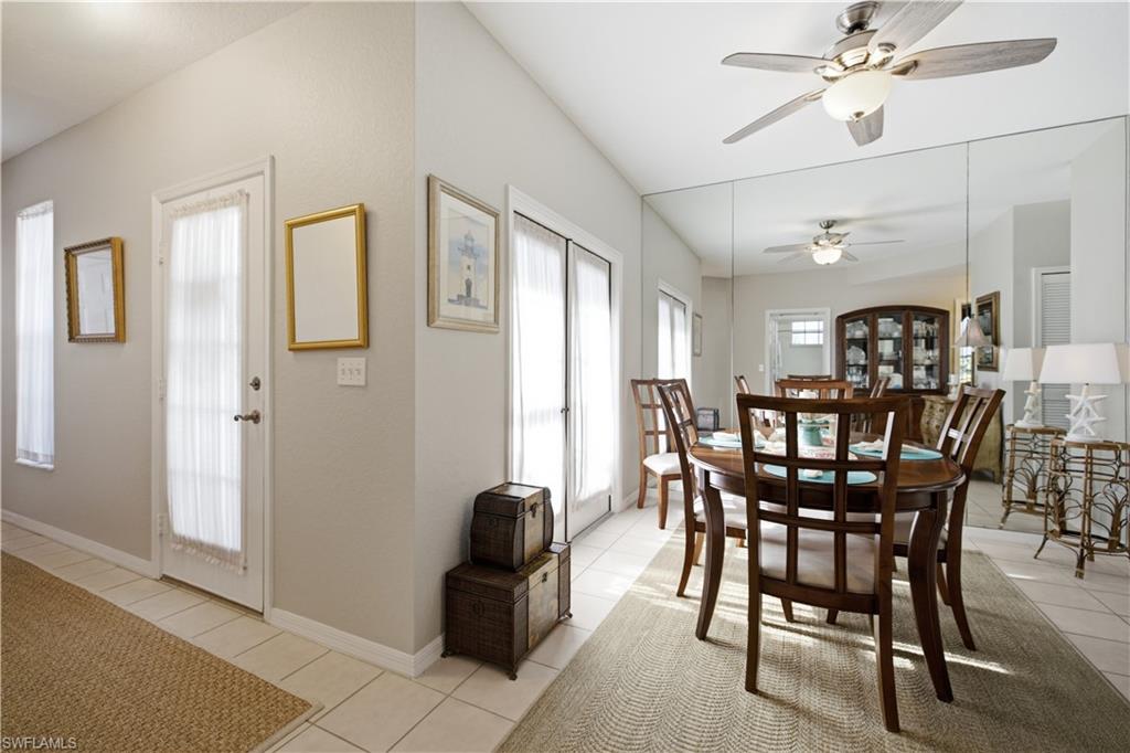Dining area featuring a ceiling fan with integrated lighting, a full mirrored wall, and tile flooring