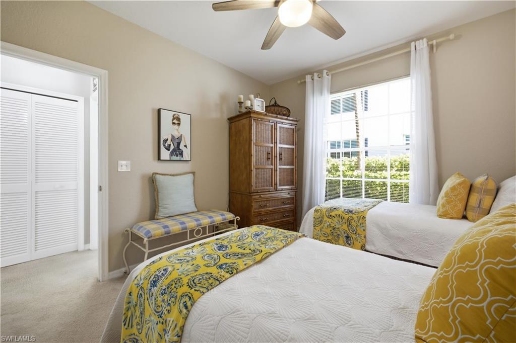 Bedroom featuring a ceiling fan, a window with white louvered blinds and sheer curtains, and light neutral-toned carpeting