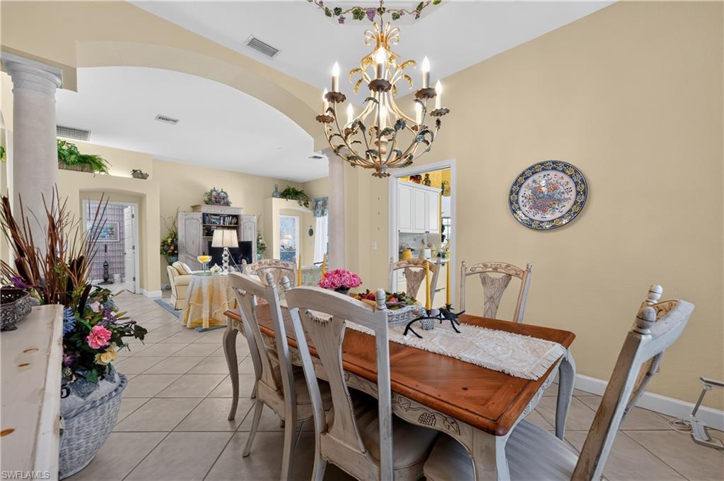 Formal dining room featuring a decorative chandelier, archway, and tile flooring