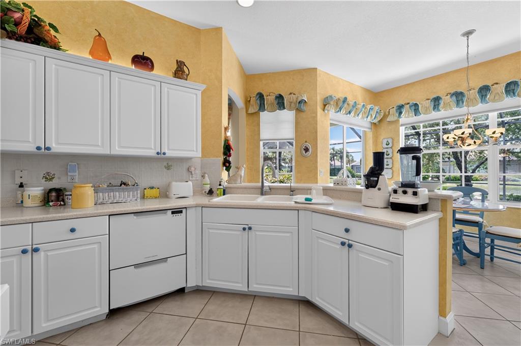 Kitchen featuring white cabinetry with blue hardware, light-toned countertops, and a tiled backsplash