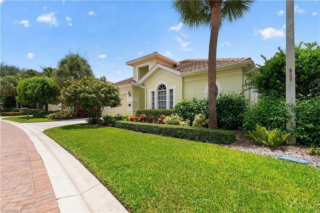 Exterior featuring a light yellow stucco finish, arched windows, and a terracotta tile roof