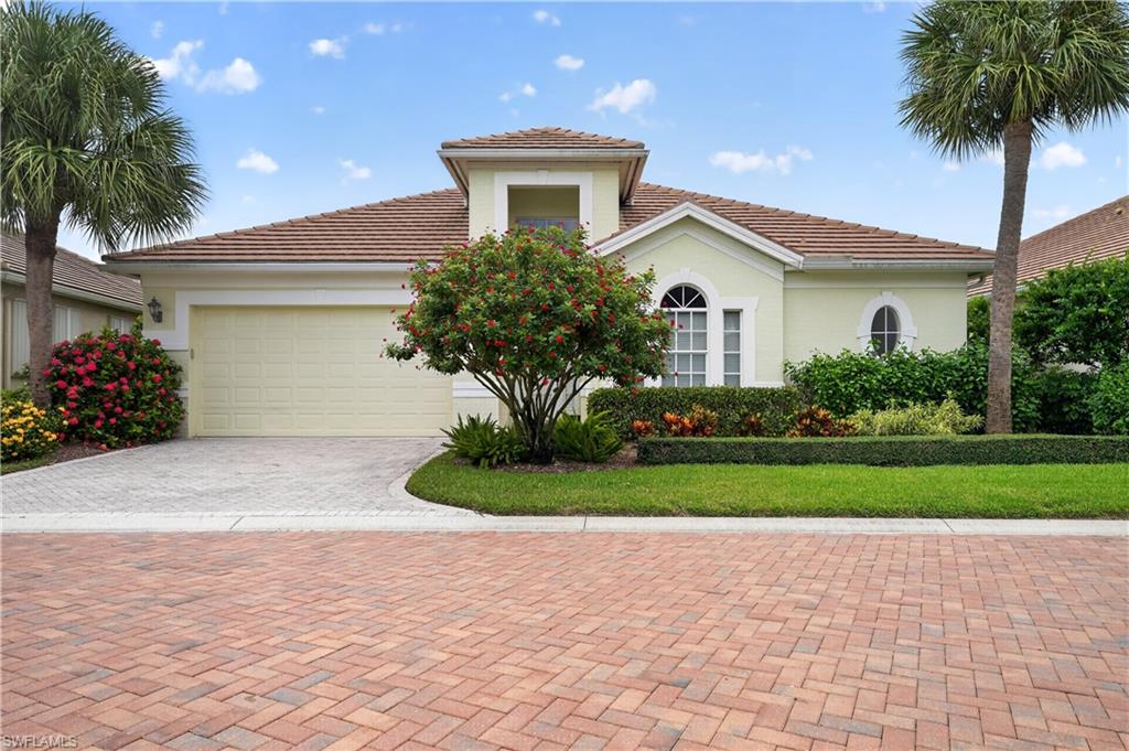 Mediterranean-style residence featuring a tile roof, light-toned exterior, and an attached garage