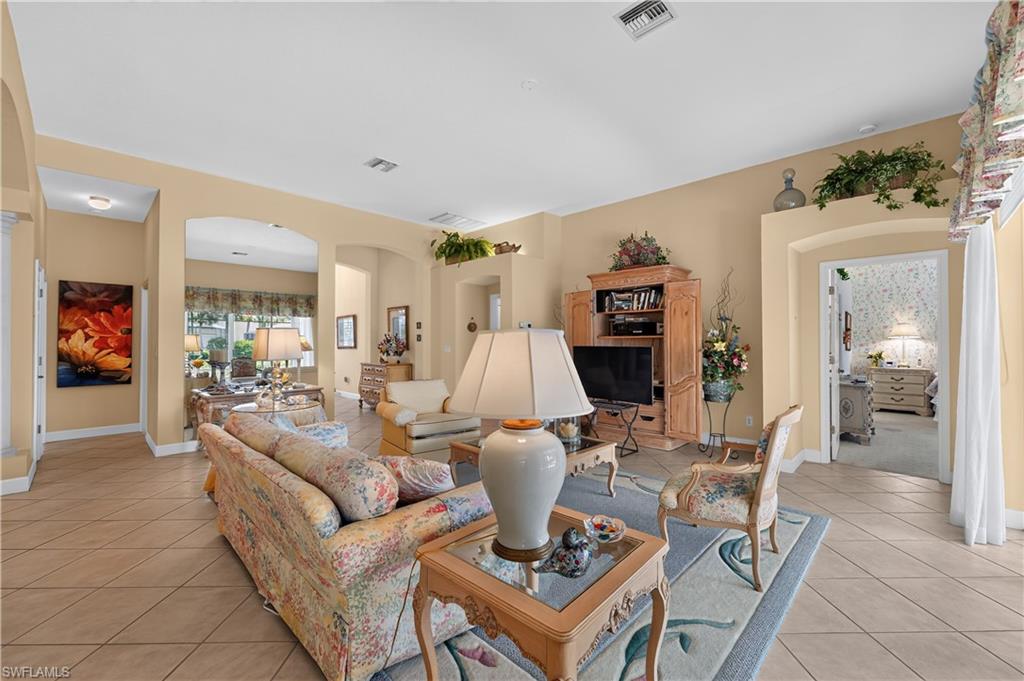 Open concept living area featuring tile flooring, vaulted ceilings, arched doorways, and built-in display ledges