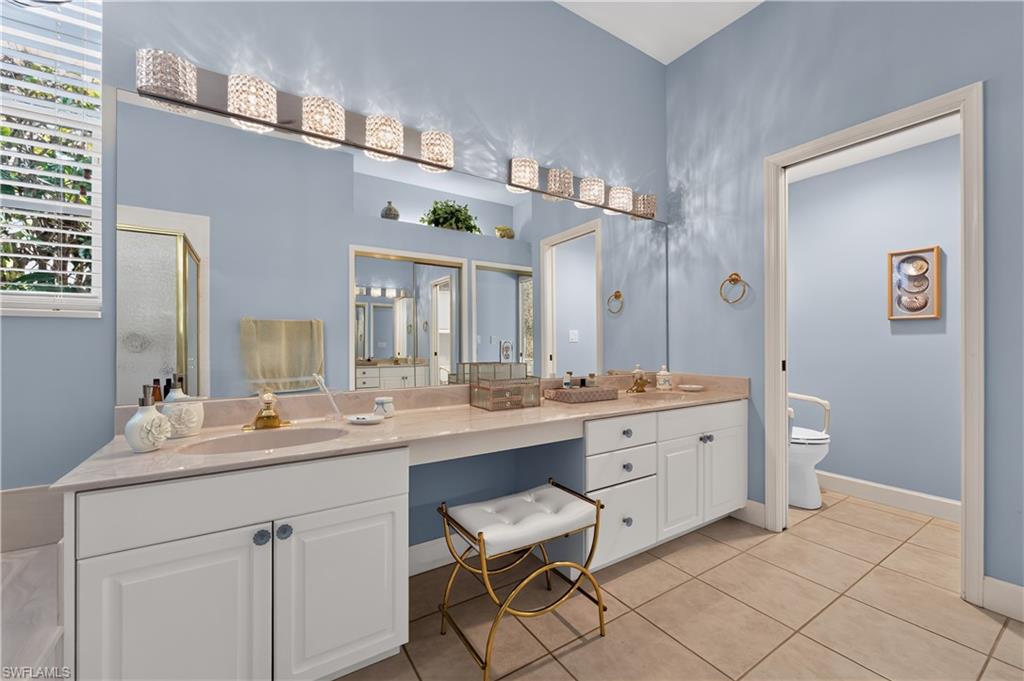 Dual vanity with a built-in dressing table, framed by a large mirror and illuminated by a multi-bulb fixture