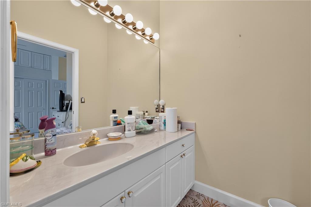 Vanity with an integrated sink, light-toned countertop, and white cabinetry featuring gold-toned hardware