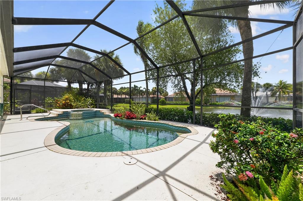Screened lanai featuring a freeform swimming pool with integrated spa and waterfall