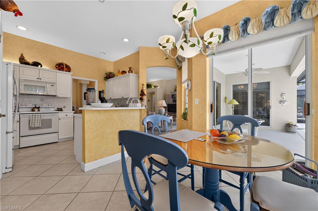 Kitchen and dining area featuring tile flooring, white cabinetry, a built-in breakfast bar, and glass sliding doors opening to an outdoor patio