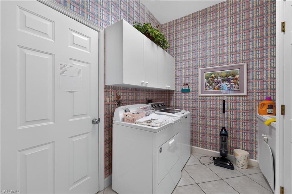 Dedicated laundry area featuring white upper cabinetry, a white panel door, and tiled flooring